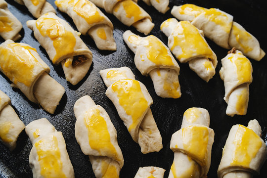 Raw serbian kifla cheese crescent rolls egg glazed homemade ready to bake high angle view on black casserole dish