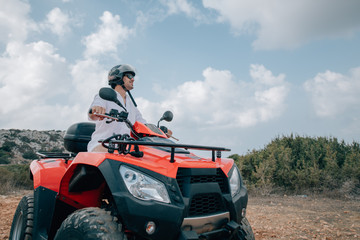 A man sits on a quad in a helmet and glasses in the mountains © Anna