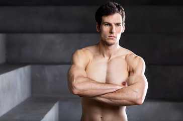 Portrait of a muscular handsome bodybuilder standing with crossed arms.