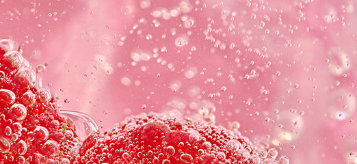 Close up of red objects in pink liquid with bubbles