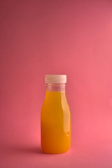 Orange juice bottle on orange background, vertical