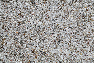 Stucco texture with small stones, pebbles on the wall. Background for design.