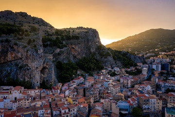 Fototapeta premium Panoramic view of the city of Cefalu from the sea. Contour light from the sun at dawn. Tyrrhenian Sea. Sicily, Italy