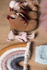 Baby girl stuff with pink dress and many textile toys on a wooden background