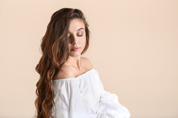 Beautiful woman with curly hair on light background