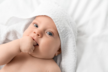 Fototapeta na wymiar Portrait of cute little baby with towel lying on bed