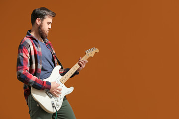 Young man playing guitar on color background