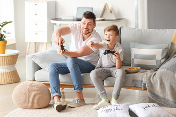 Father and his little son playing video games at home