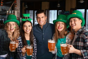 Young friends with beer celebrating St. Patrick's Day in pub