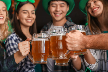 Young friends with beer celebrating St. Patrick's Day in pub