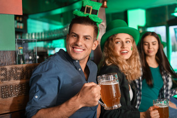 Young man with friends celebrating St. Patrick's Day in pub