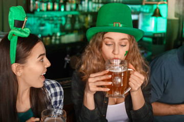 Young women with beer celebrating St. Patrick's Day in pub