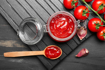 Jar with tasty tomato sauce on table
