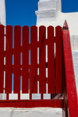 Old red wooden fence door of a mediterranean Greek island white house in Mykonos, Cyclades, Greece