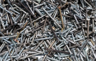 High angle full frame close-up view of a piled up large amount of new and used screws
