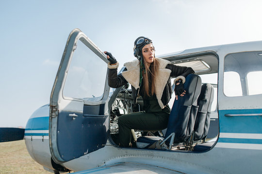 a girl in a special pilot s headdress looks out of the cockpit with a side panel