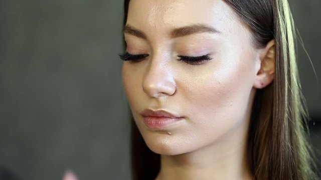 Makeup artist paints eyelashes of the beautiful model. The process of applying makeup.