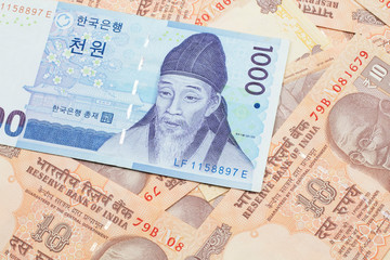 Fototapeta premium A blue South Korean one thousand won bank note close up in macro on a background of Indian ten rupee bank notes