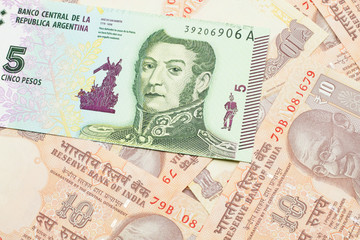 Obraz na płótnie Canvas A five peso bank note from Argentina on a background of Indian ten rupee bank notes close up