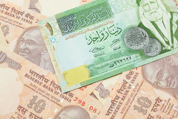 A macro image of a one dinar bank note from Jordan on a bed of Indian ten rupee bank notes close up