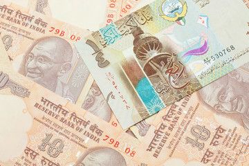 Fototapeta na wymiar A colorful quarter dinar bank note from Kuwait close up in macro with Indian ten rupee bank notes