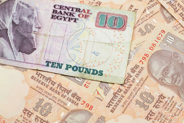 A close up image of an Egyptian ten pound bank note with Indian ten rupee bank notes in macro