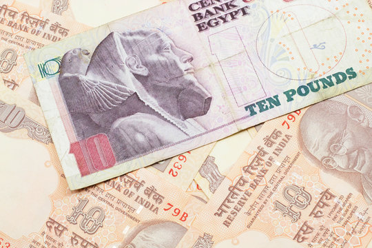 A close up image of an Egyptian ten pound bank note with Indian ten rupee bank notes in macro