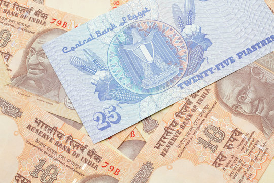 A close up image of an Egyptian twenty five pisatres note with Indian ten rupee bank notes in macro