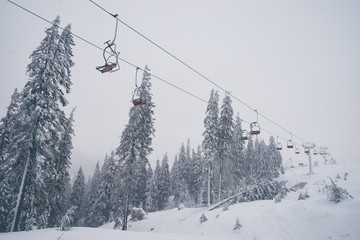 Ski lift with seats going over the mountain and paths from skies and snowboards.