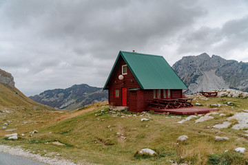Lonely red house with a green roof in the mountains by the road. Remote places to travel.