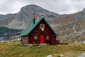 Fototapeta na wymiar Lonely red house with a green roof in the mountains by the road. Remote places to travel.
