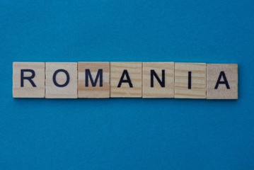 gray word romania from small wooden letters on a blue table