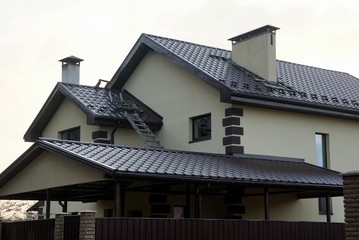 facade of a private house with windows on a gray wall under a brown tiled roof