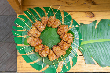 cooked grilled roasted pork sticks are arranged on the banana leaf and decoration food around this snack area for a seminar breaking time at outside garden.