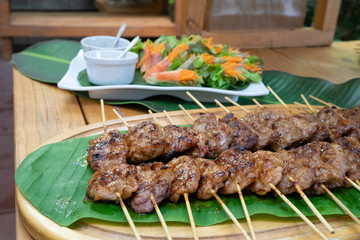 cooked grilled roasted pork sticks are arranged on the banana leaf and decoration food around this snack area for a seminar breaking time at outside garden.