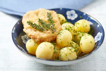 Pork Schnitzel with potatoes and fresh herbs.	