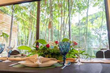 Luxury Lunch or Dinner set on the long table pattern with a black cover table with flower decoration.