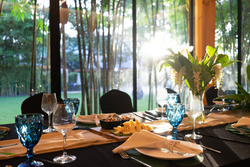 Luxury Lunch or Dinner set on the long table pattern with a black cover table with flower decoration.