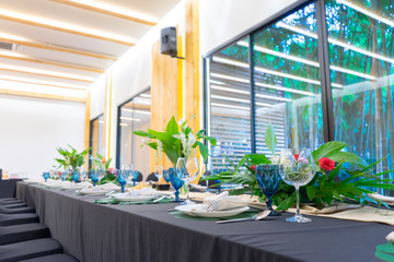 Luxury Lunch or Dinner set on the long table pattern with a black cover table with flower decoration.