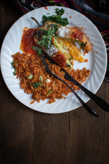 Chiles rellenos and Mexican rice in white dish on wooden table