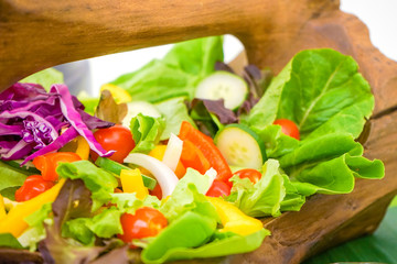 Mixed green red yellow and colourful vegetables slideed and arranged into bowl and wood basket bundle together ready for lunch or dinner.