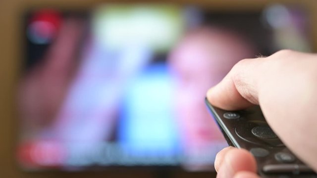 Watch TV. Close-up of a man watching and turning off the television, television ponel on the background. Interactive tv