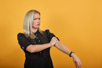 Young blonde girl in black dress on yellow background determined woman rolls up her sleeves