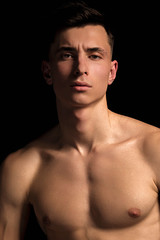 Naklejka premium Handsome wet sport sexy stripped guy portrait with waterdrops and smoke on isolated black background