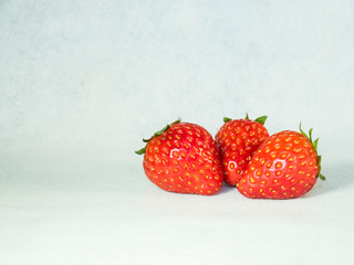 Three ripe strawberry fruits on a white background.