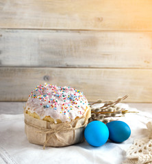 Easter cake on a light background, in a rustic style with blue eggs and beautiful sprigs of willow on a white napkin with a Sunny mood. Copy space