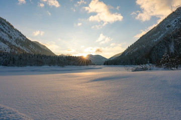 beautiful sunset in the mountains Alps in winter - with a blue yellow heaven - sunset between the mountains Germany Lödensee -  reflection in snow - winter landscape