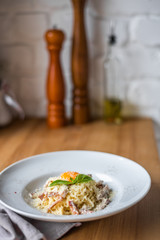 Spaghetti carbonara with pancetta, eggs and cheese in white bowl on the wooden table