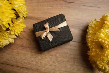 Obraz na płótnie Canvas Gift box on the wood background with a yellow flowers. Holiday surprise. Lifestyle. Holiday card.