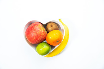 Heart-shaped bowl with fruit isolated on white background. The concept of healthy eating, eating fruit. Bowl with apple, mandarin banana. A bowl filled with fruit. Fruit and vitamins for the heart.